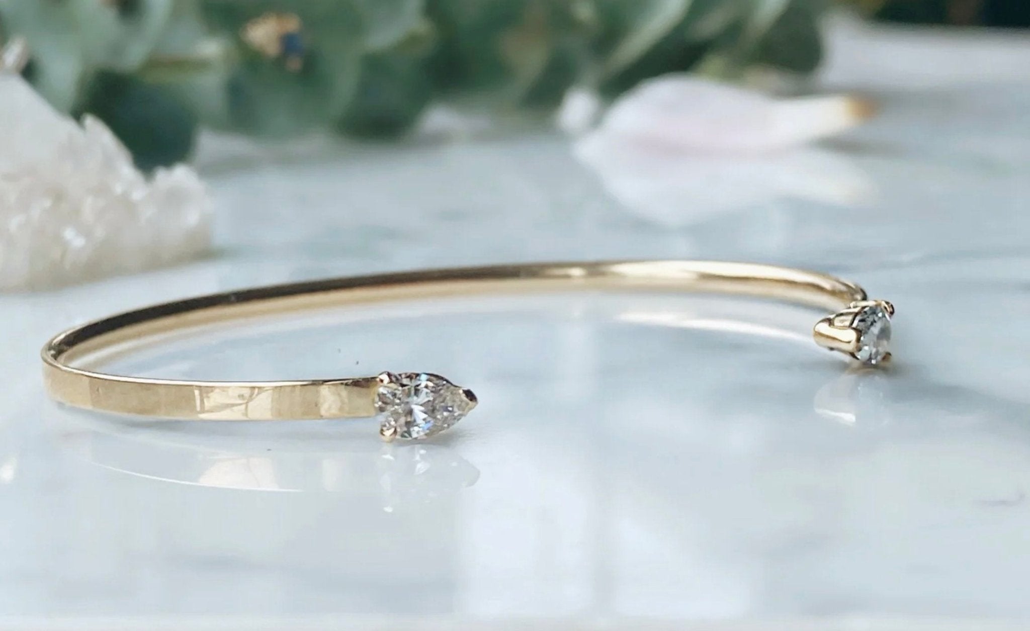 open gold bangle with pear shaped diamonds on marble background - Camille Jewelry