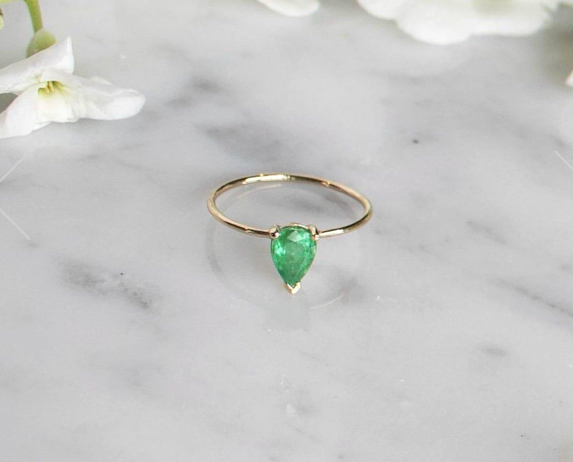 pear shaped emerald gold ring on marble background- Camille Jewelry