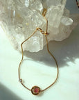 Gold filled bracelet with a pink tourmaline gemstone on a light quartz background by Camille Jewelry.
