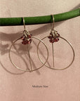 Gold filled threader hoop earrings in garnet rondelles on a soft background.
