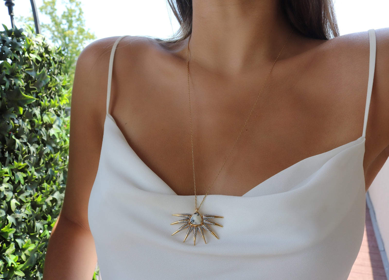 Woman outside wearing the Phoenix Wing Pendant wearing a white top