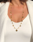 Gold plated disc charm convertible necklace worn long on a model with white clothes by Camille Jewelry.