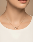 Woman wearing a diamond interlocking heart necklace in 14K gold by Camille Jewelry