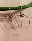 Gold filled threader hoop earrings in garnet rondelles on a soft background.