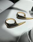 Phoenix Jewelry shown of Black Spinel Beak Crossover Rings laying on a book display by Camille Jewelry