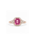 An emerald-cut pink sapphire ring in rose gold, surrounded by a halo of small clear stones and a three-stone diamond band, shown on a plain white background.