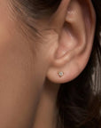 Tiny diamond stud earring in yellow gold worn on model’s ear, Camille Jewelry