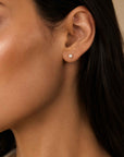 Woman wearing tiny pearl stud earrings in 14K gold in a second hole by Camille Jewelry