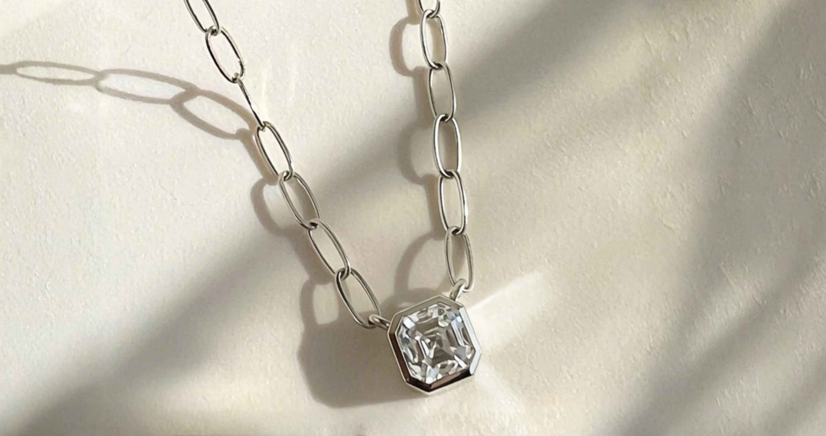 sterling silver necklace with asscher cut moissanite gemstone that is bezel set on a light naturally lit background by Camille Jewelry