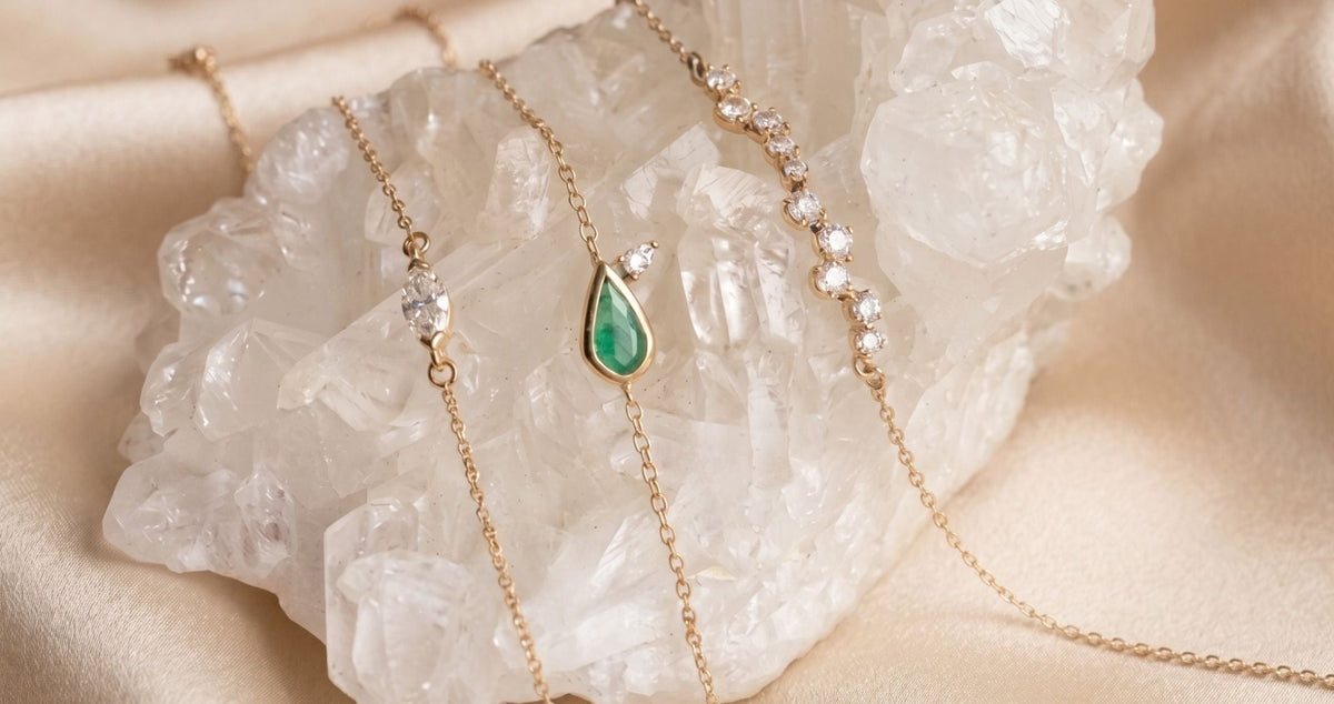 14k solid gold jewelry of diamonds and gemstone bracelets on a quartz display and beige background by Camille Jewelry