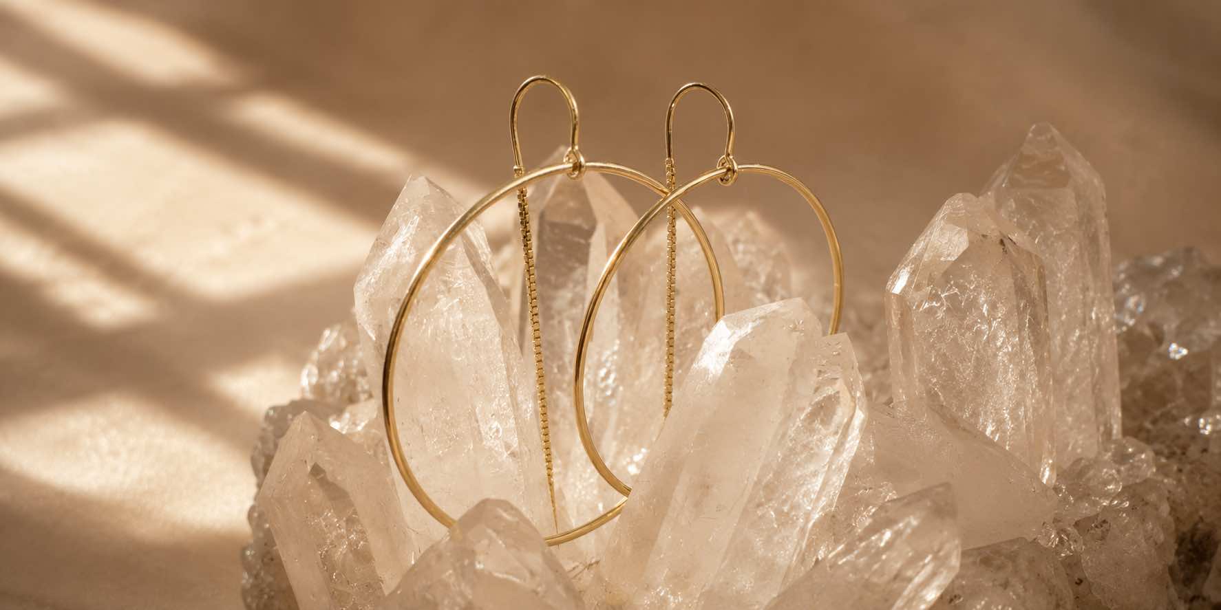 Gold threader hoop earrings on quartz display for Camille Jewelry