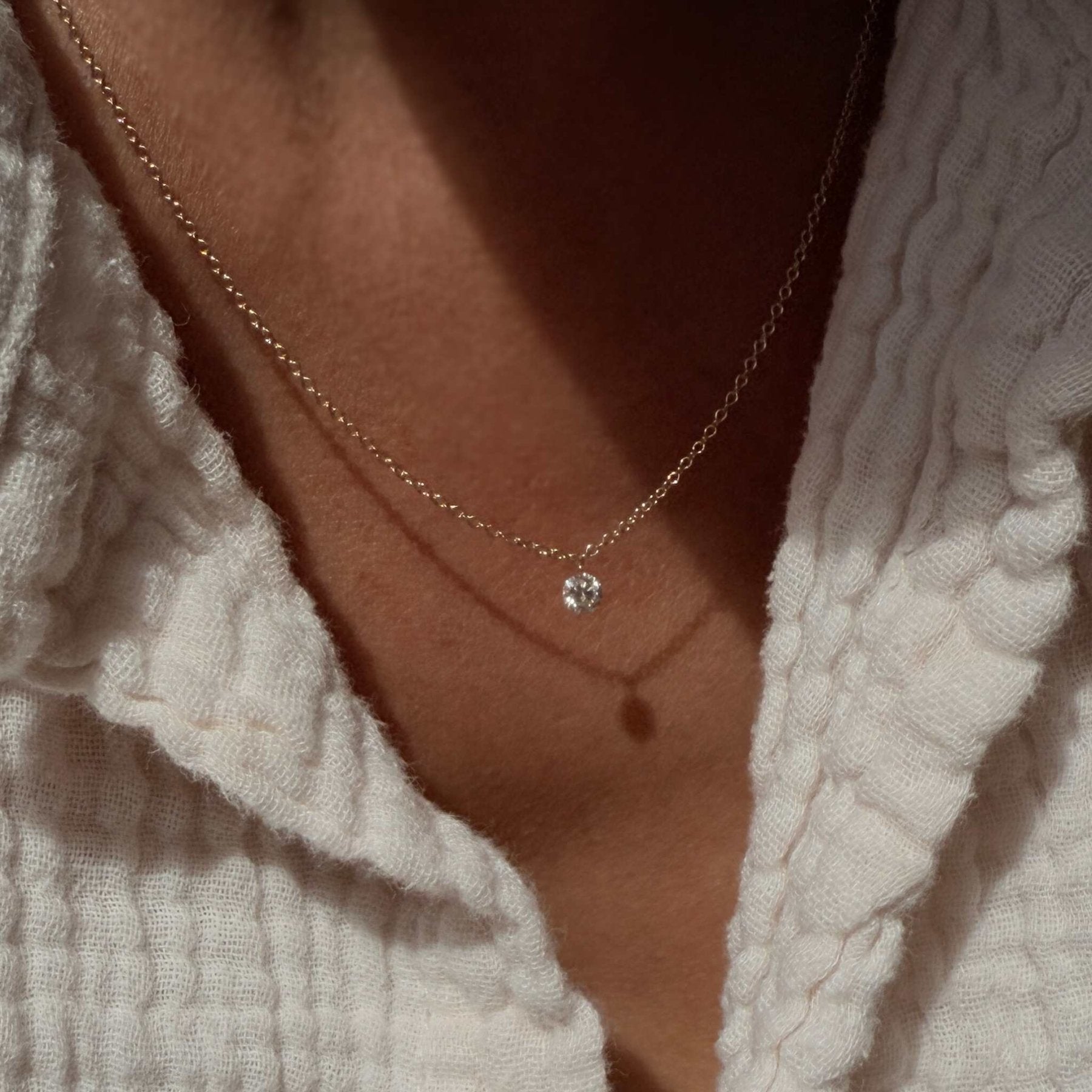 Woman wearing a floating diamond necklace in solid 14K yellow gold by Camille Jewelry