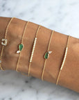 Diamond Emerald Bracelet – 14K Gold pear shaped Jewelry with other diamond bar and initial bracelets on wrist by Camille Jewelry