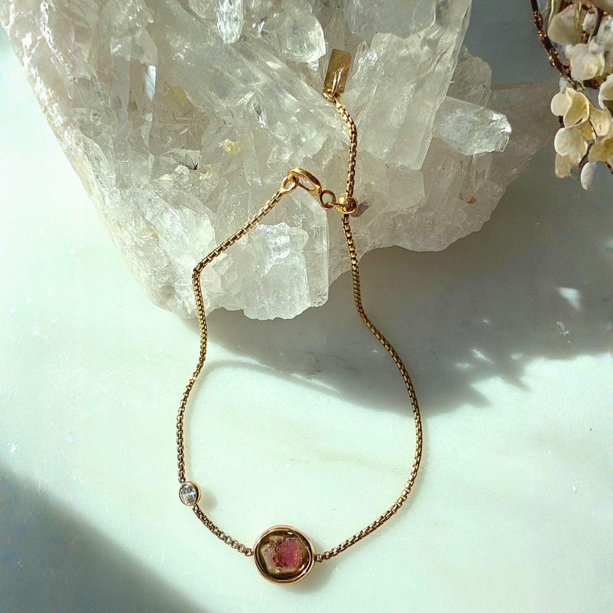 Gold filled bracelet with a pink tourmaline gemstone on a light quartz background by Camille Jewelry. 