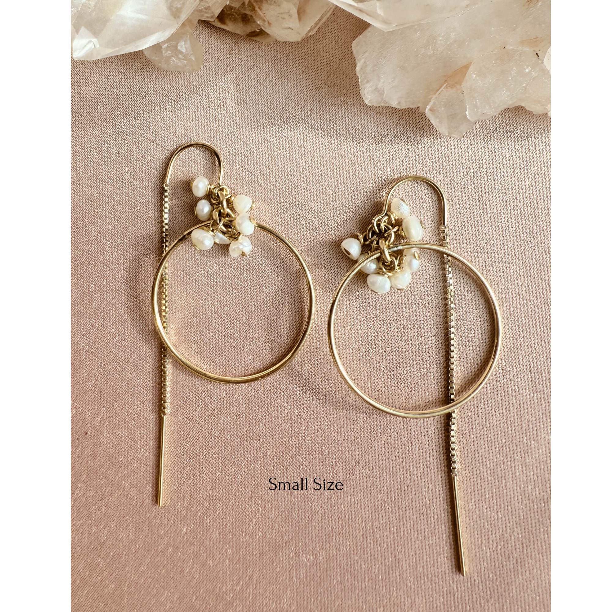Gold filled threader hoop earrings in fresh water pearl rondelles on a flat view on a pink background. 