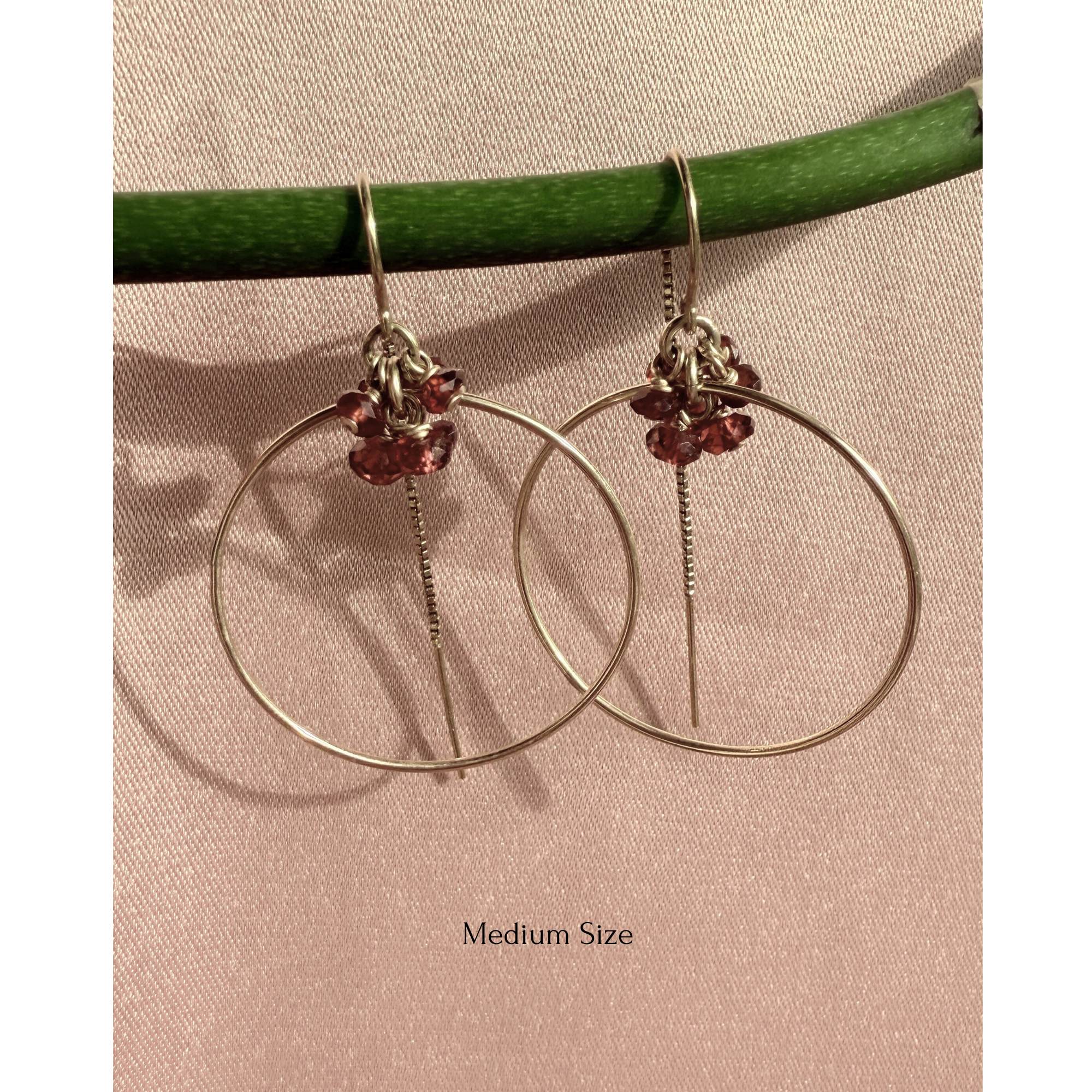 Gold filled threader hoop earrings in garnet rondelles on a soft background. 