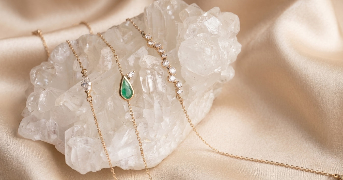 Jewelry gifts $500-$1000 in gold, diamonds and emeralds on a quartz stone and beige background by Camille Jewelry
