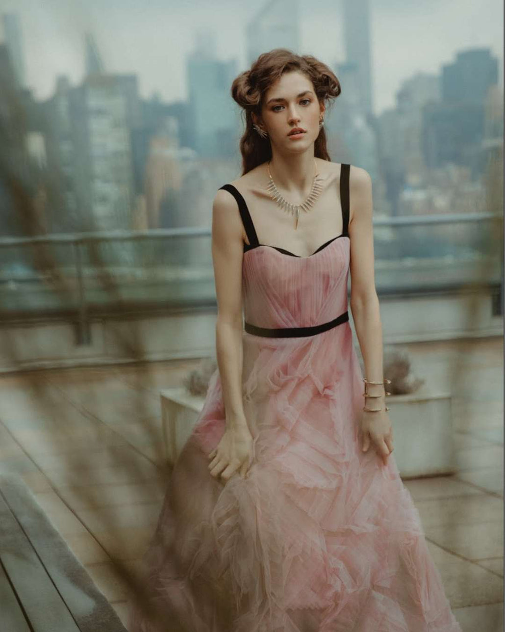 Woman in a pink dress with black straps on a rooftop with cityscape background editorial photo shoot featuring Camille Jewelry. 
