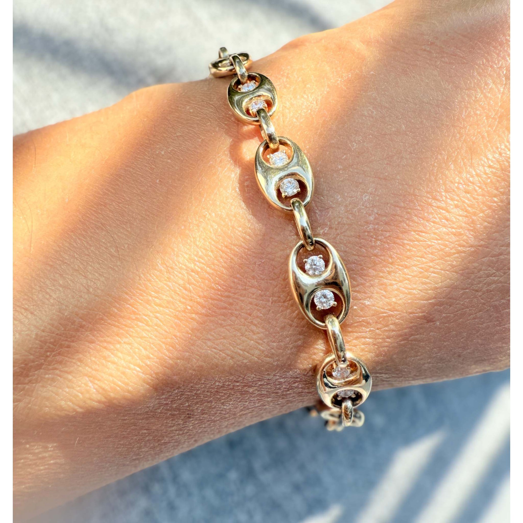 Gold mariner bracelet with diamond accents on a wrist against a neutral background by Camille Jewelry