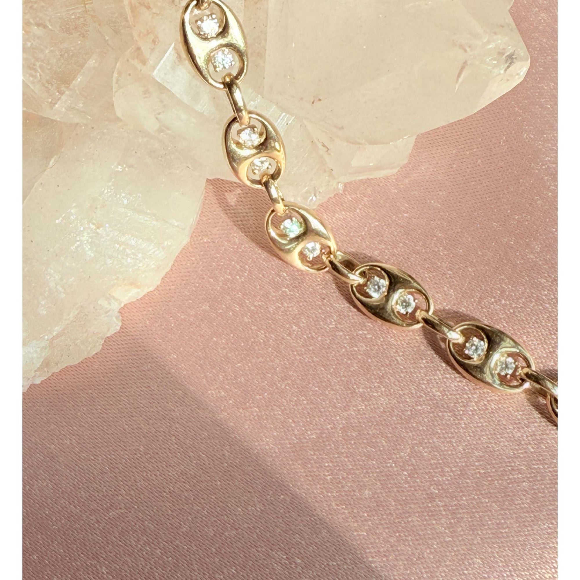 Gold mariner bracelet with diamond accents on a pink fabric background by Camille Jewelry