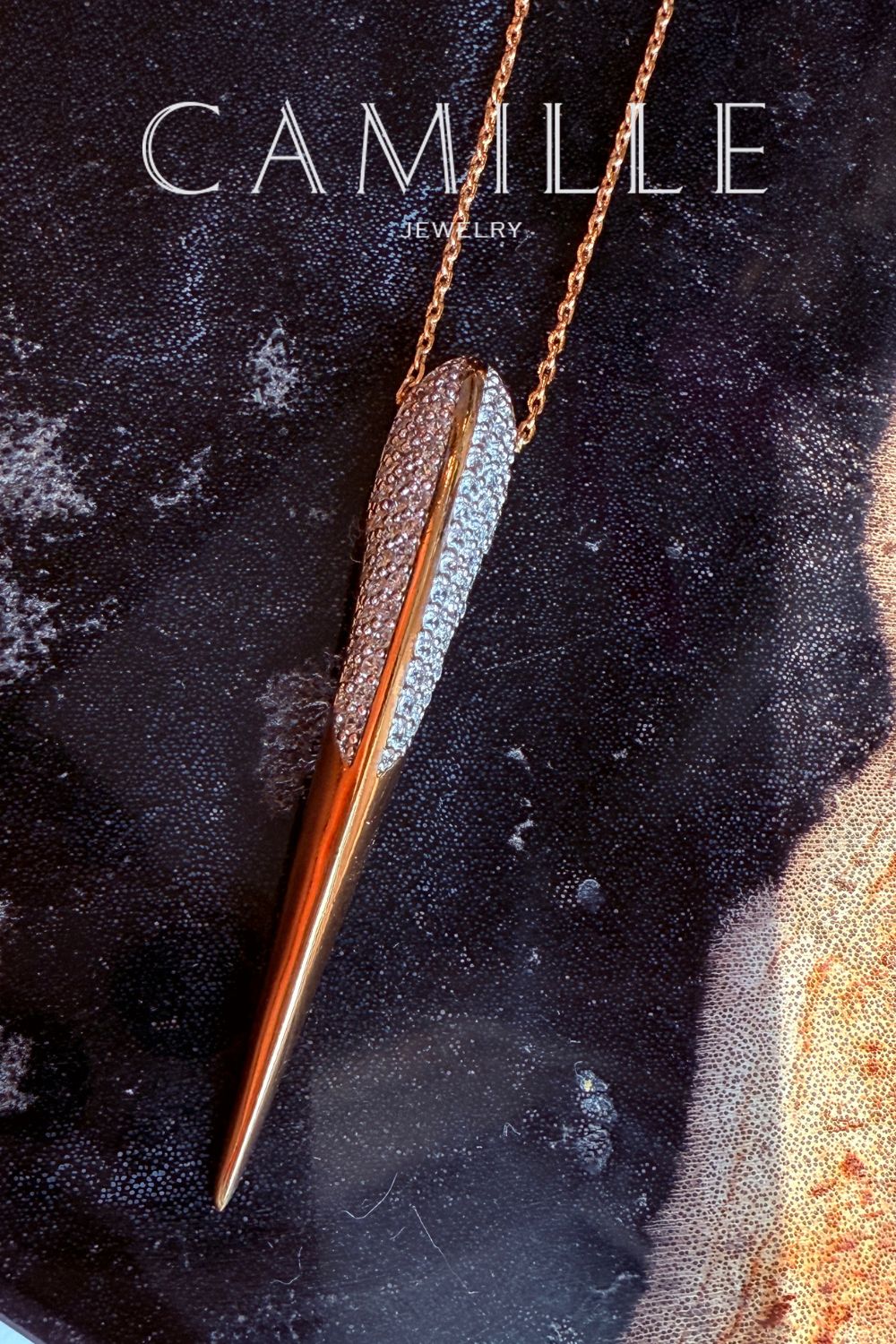 Phoenix bird beak necklace in gold on a black display with Camille Jewelry logo overlay. 