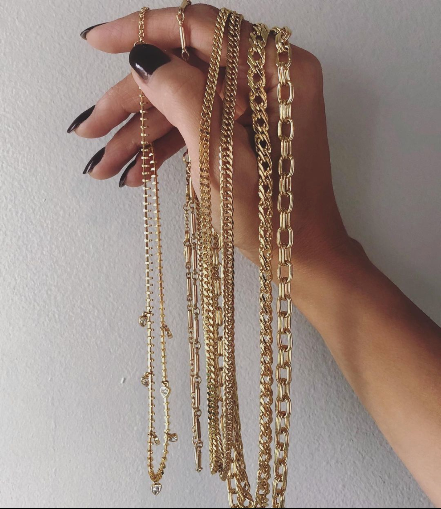 Hand holding gold fashion jewelry necklaces | Camille Jewelry