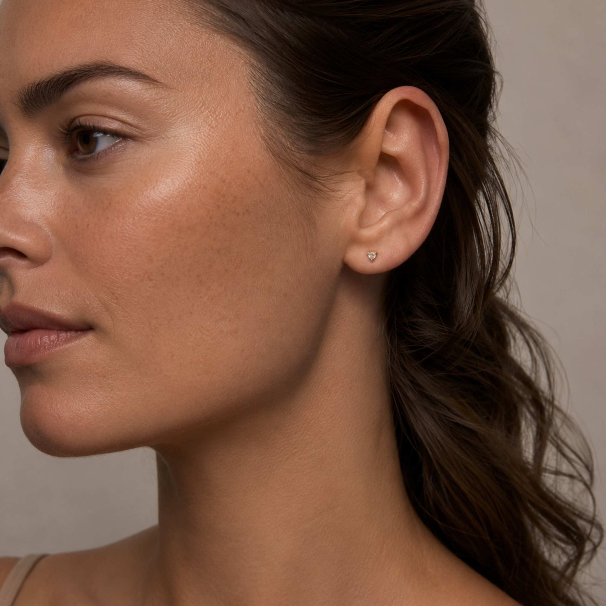 Tiny diamond stud earring in yellow gold worn on model’s ear, Camille Jewelry