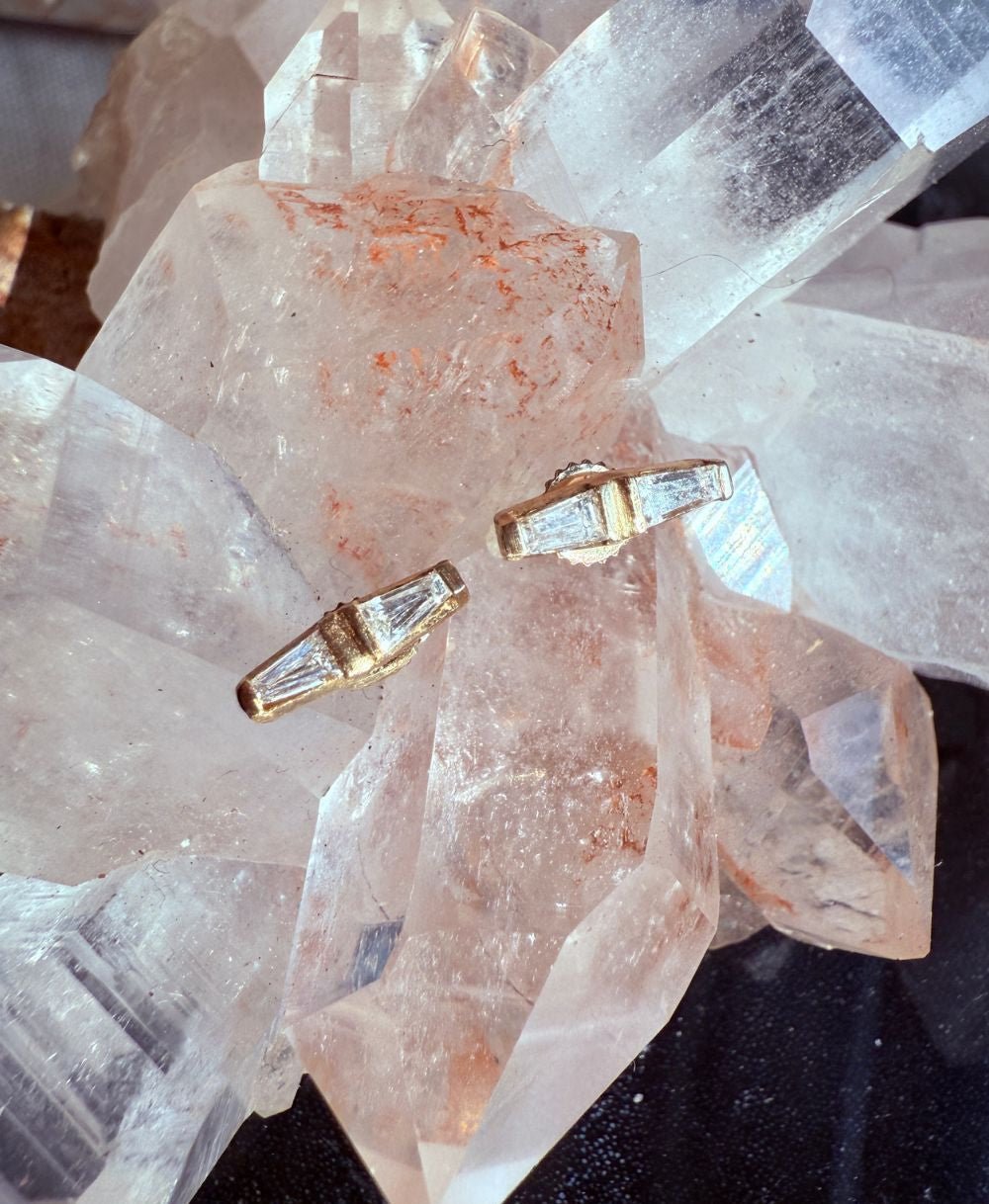 14K yellow gold tapered baguette diamond stud earrings on a quartz display by Camille Jewelry