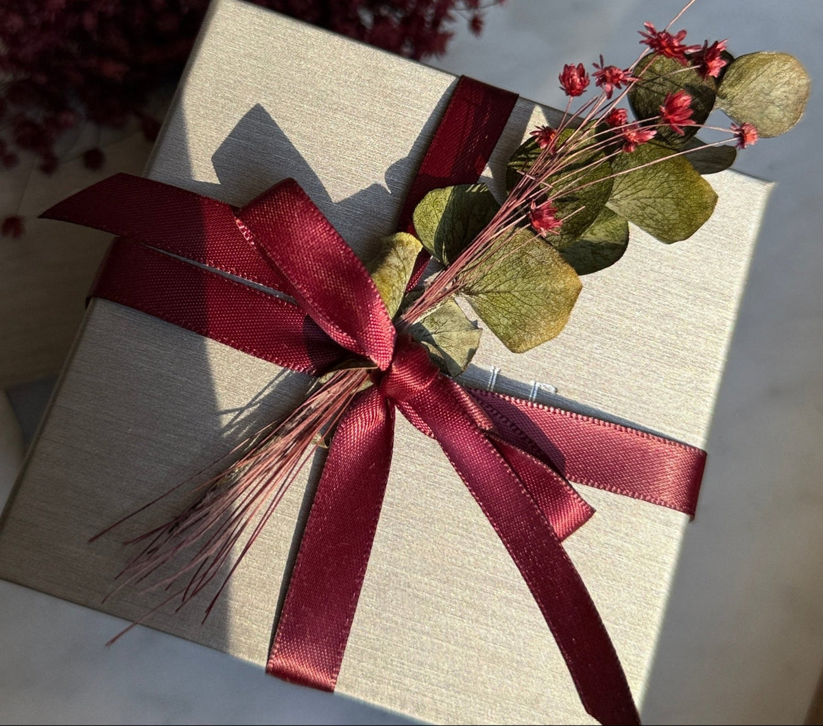 Camille Jewelry gift card box of gray silk paper and burgundy ribbon.