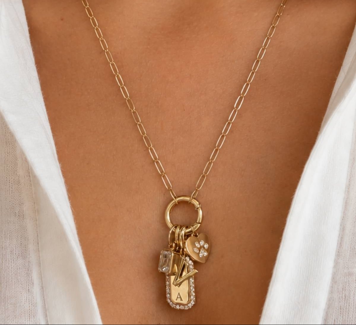 Gold jewelry for women who is wearing personalized charms on a models close up neckline by Camille Jewelry. 