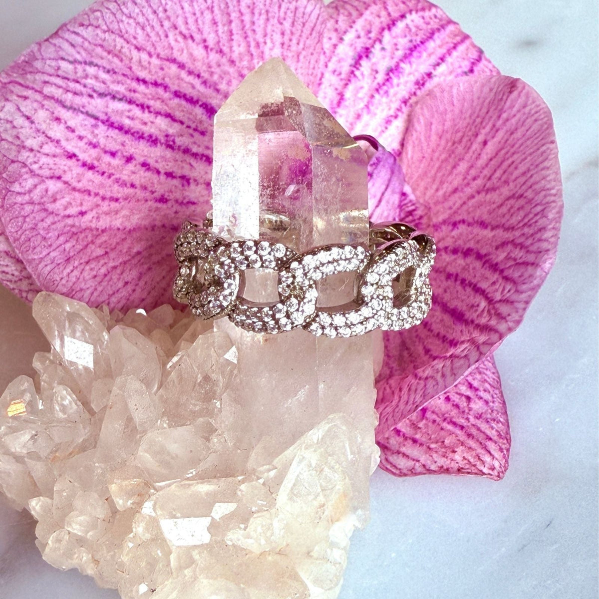 Sterling Silver Curb Chain Pavé Ring on a quartz display with orchid flower– Semi-Fine Statement Jewelry - Camille Jewelry