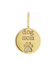 A 14k yellow gold round diamond paw print charm engraved with 'dog mom', shown on a plain white background, by Camille Jewelry
