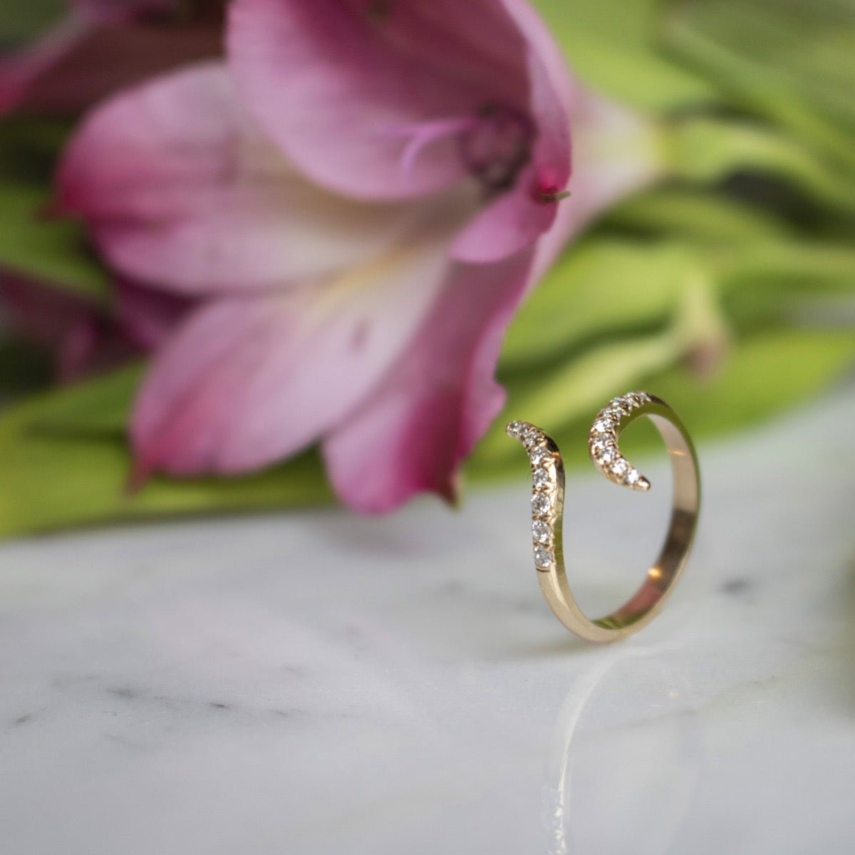 Diamond and Gold Pinky Ring for Women on display with a flower in background by Camille Jewelry.