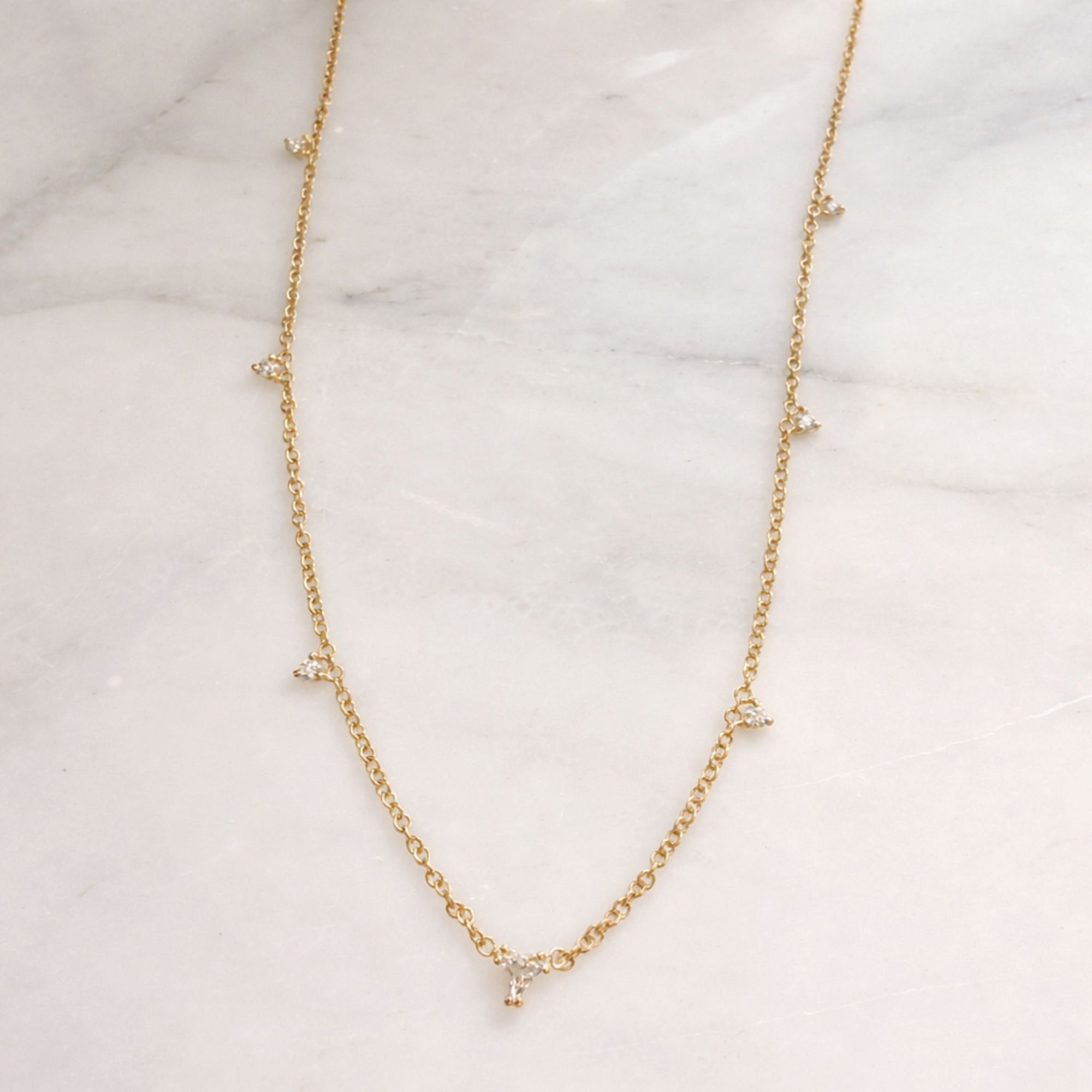 layering diamond necklace styling on marble display - Camille Jewelry