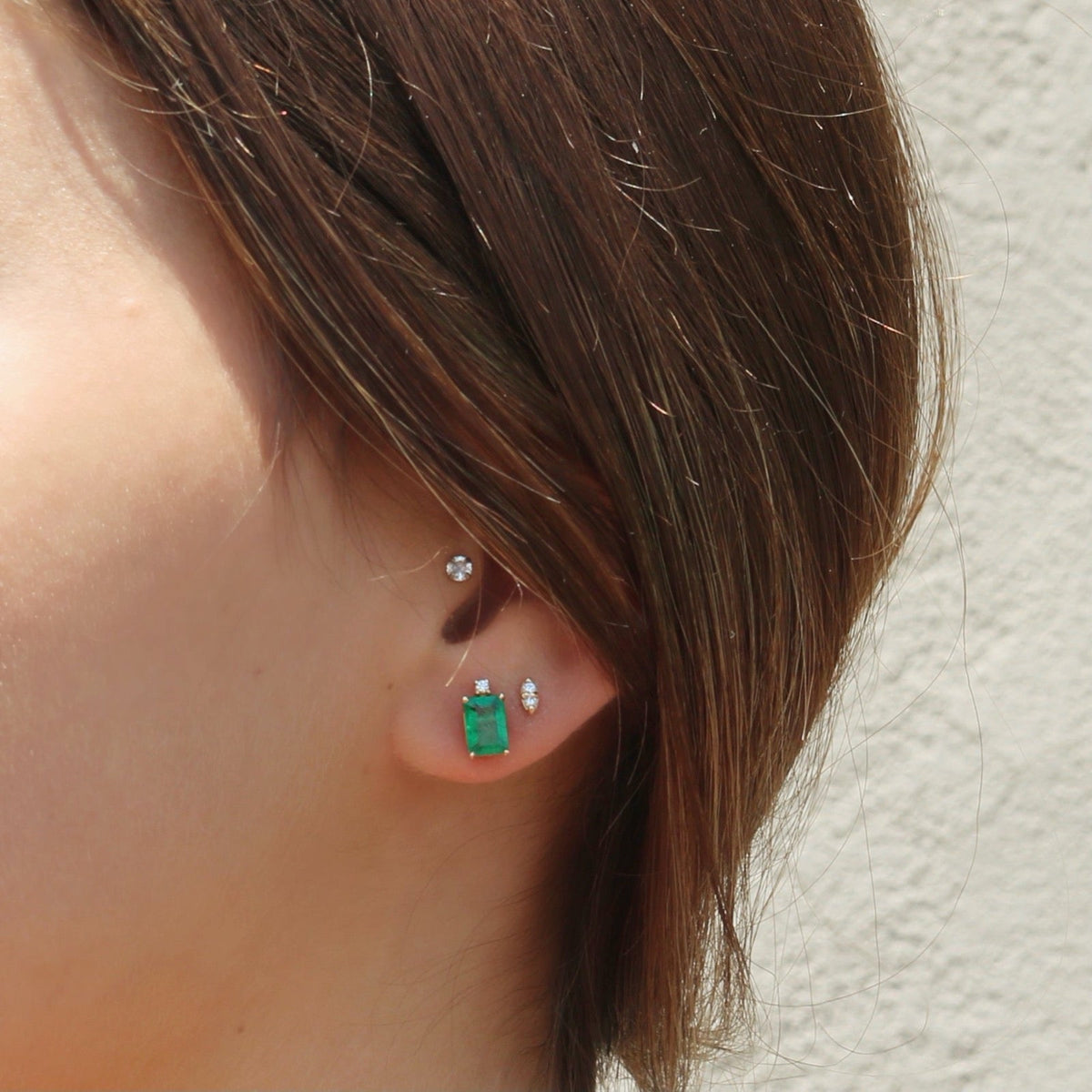 14K yellow gold Emerald Stud Earrings with diamond accent on models ear by Camille Jewelry