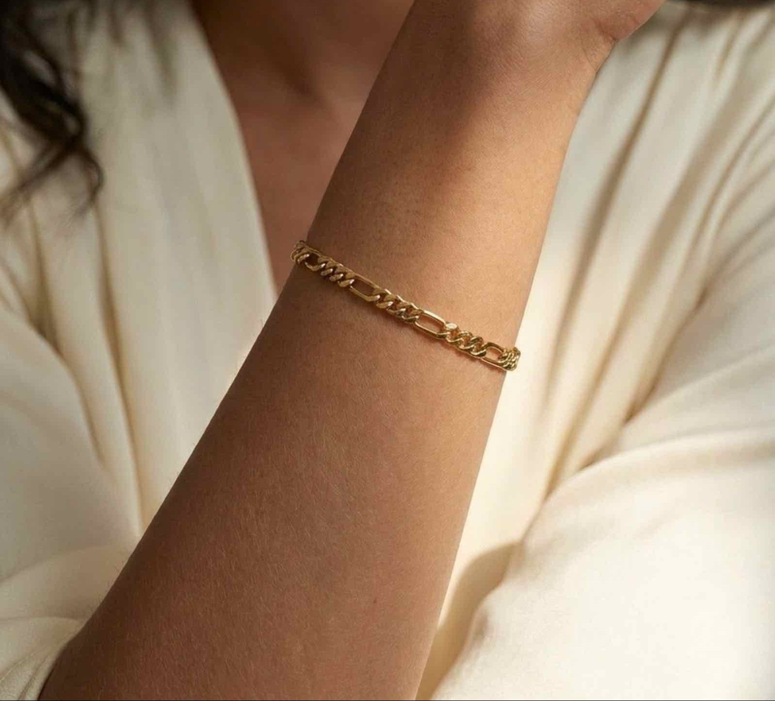 Gold filled 4mm figaro chain bracelet on models wrist close up by Camille Jewelry.