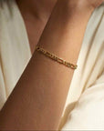 Gold filled 4mm figaro chain bracelet on models wrist close up by Camille Jewelry.