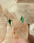Pair of kite cut lab created emerald gemstone stud earrings in 14K yellow gold on a quartz crystal background by Camille Jewelry