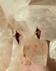 Pair of kite cut lab created ruby gemstone stud earrings in 14K yellow gold on a quartz crystal background by Camille Jewelry