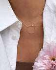 Close up of an open disk pendant with bezel set cubic zirconia on a gold filled rolo chain on model by Camille Jewelry