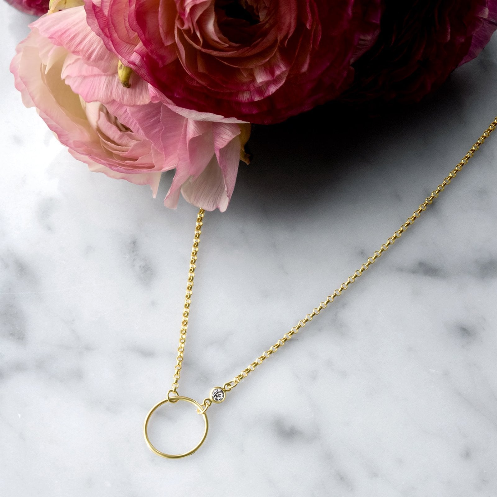 Close up of an open disk pendant with bezel set cubic zirconia on a gold filled rolo chain by Camille Jewelry