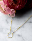 Close up of an open disk pendant with bezel set cubic zirconia on a gold filled rolo chain by Camille Jewelry