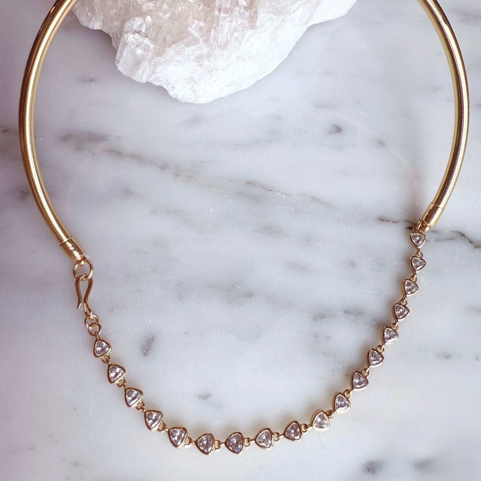 Gold Collar Tennis Necklace with trillion cubic zirconia at stones on a quartz background- Camille Jewelry