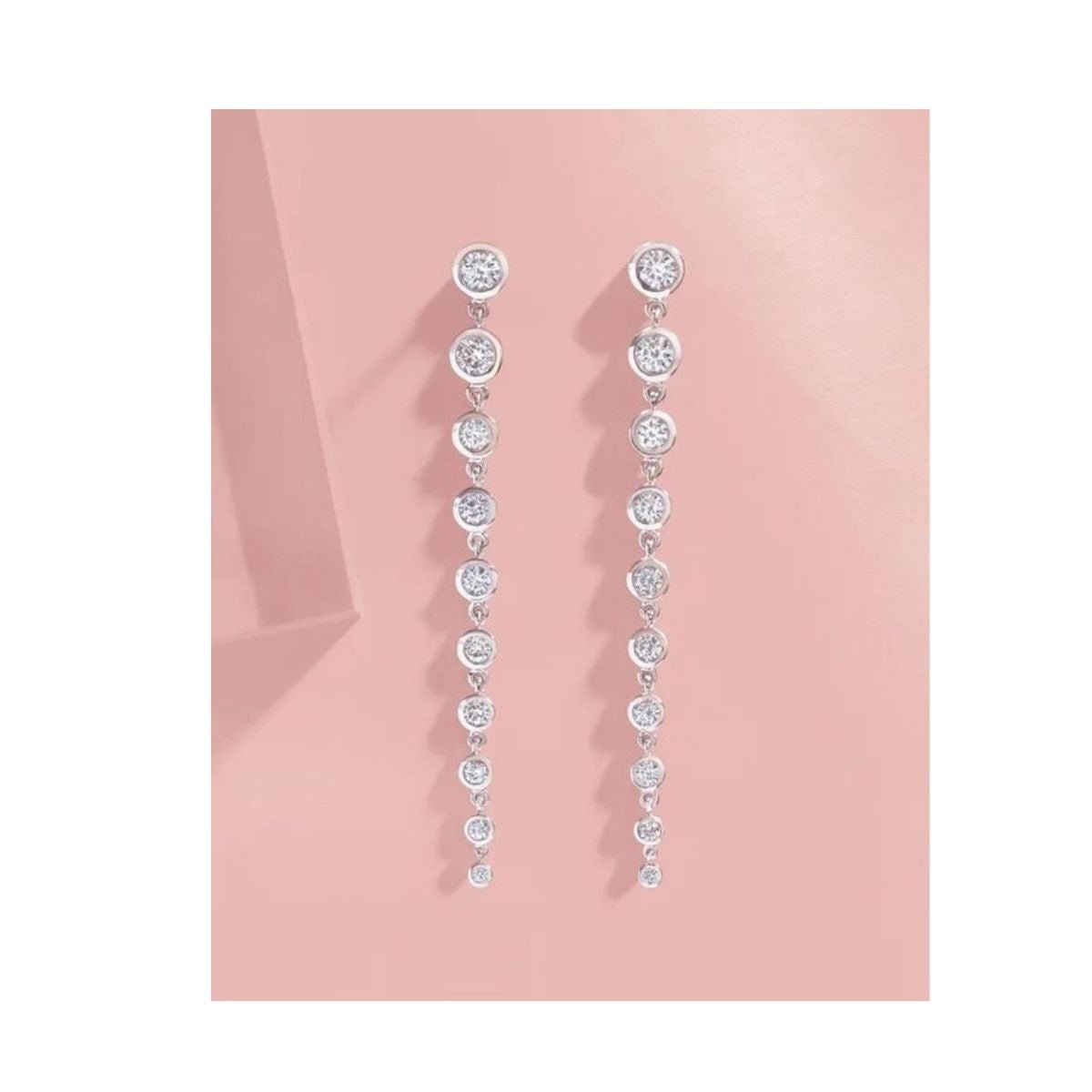 Graduated Diamond Dangle Earrings in 14K White Gold On pink background - Camille Jewelry