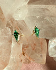Pair of kite cut lab created emerald gemstone stud earrings in 14K yellow gold on a quartz crystal background by Camille Jewelry
