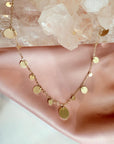 Gold plated disc charm convertible necklace and eyeglass chain displayed on a quartz stone and soft pink background by Camille Jewelry.