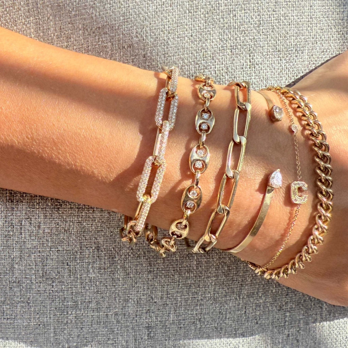 Stacked gold and diamond bracelets by Camille Jewelry worn on the wrist.