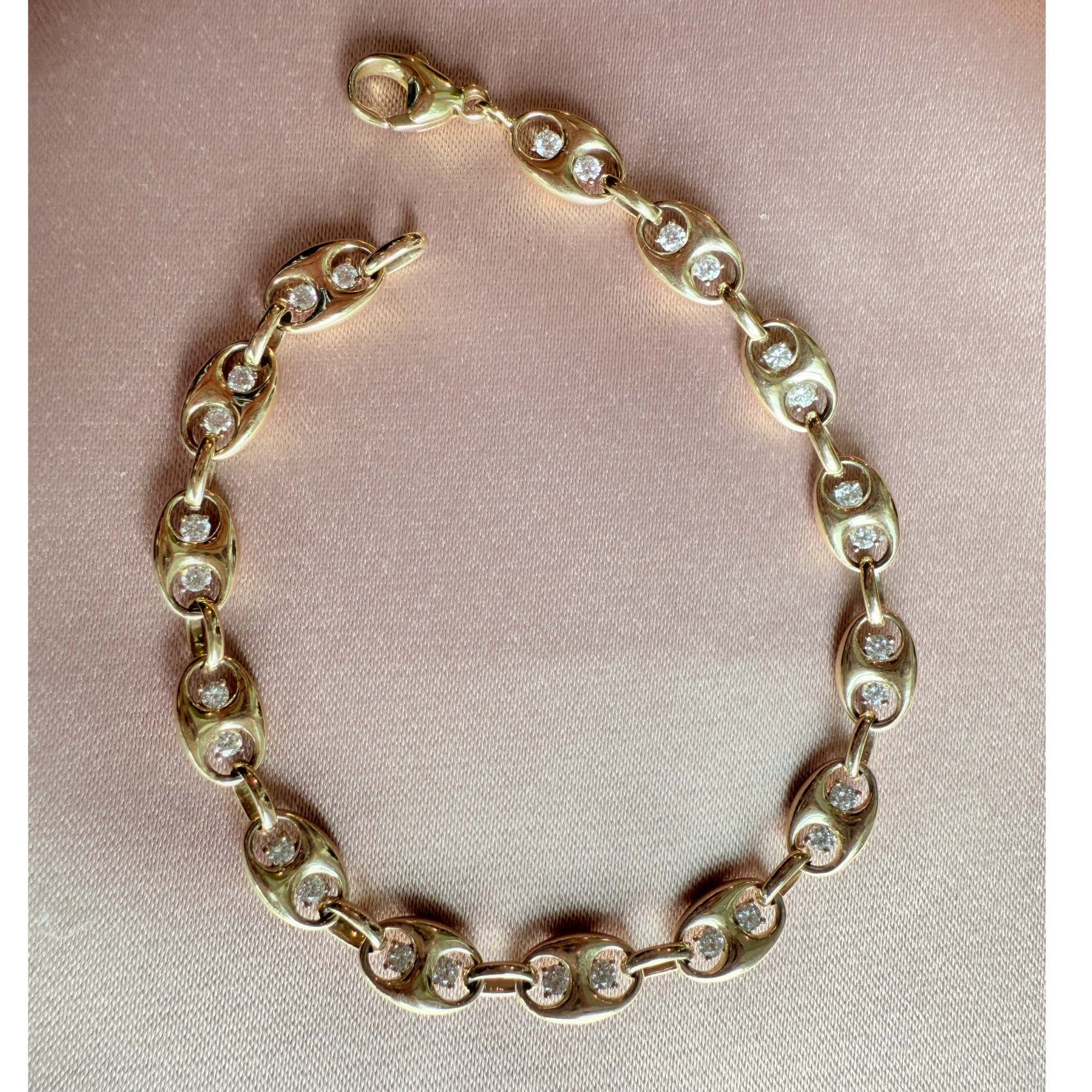 Gold mariner bracelet with diamond accents on a pink fabric background by Camille Jewelry