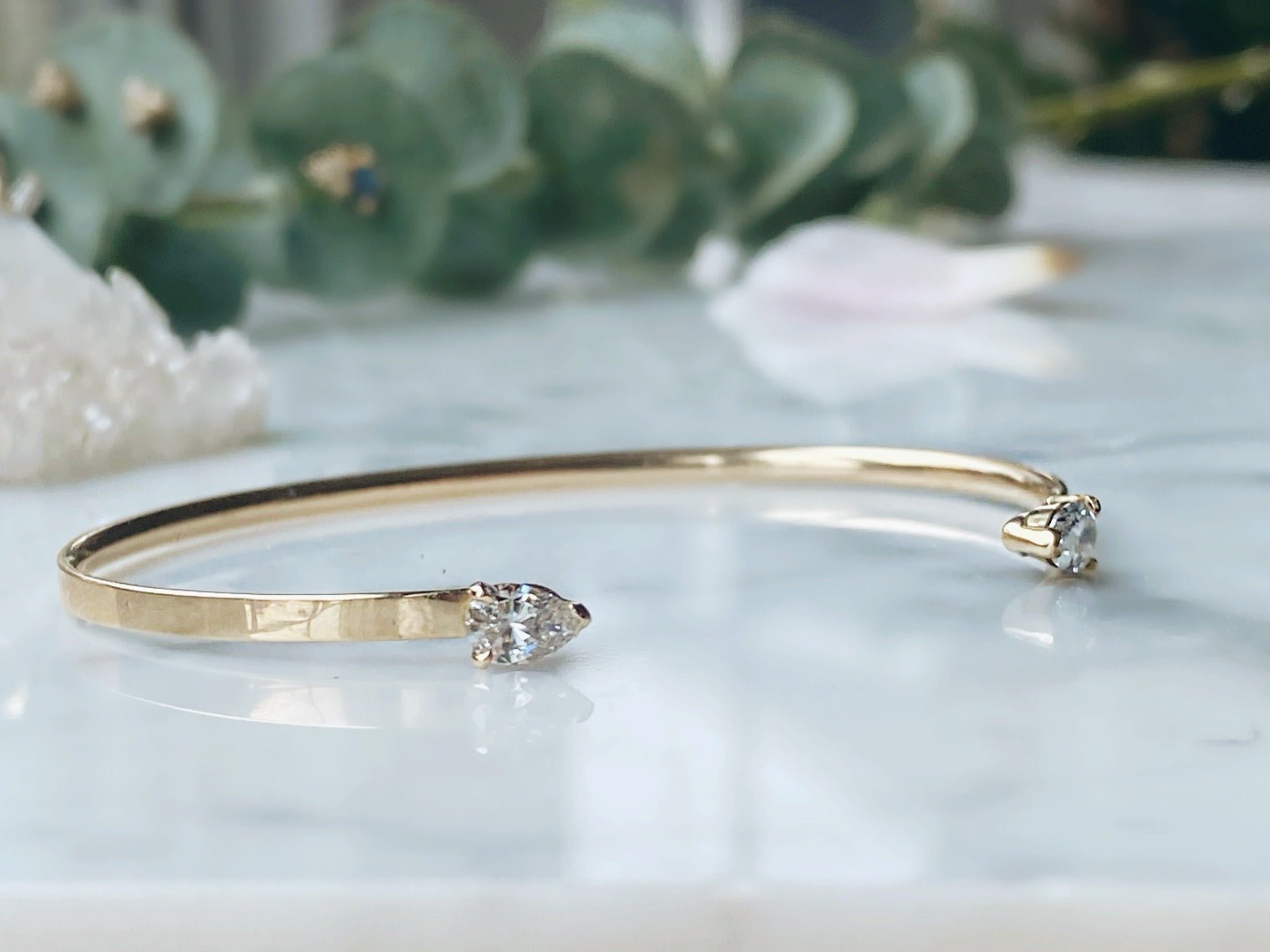 Open Cuff Bracelet | Pear-Shaped Diamond Bangle in 14K Yellow Gold on quartz display- Camille Jewelry