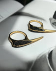Phoenix Jewelry shown of Black Spinel Beak Crossover Rings laying on a book display by Camille Jewelry